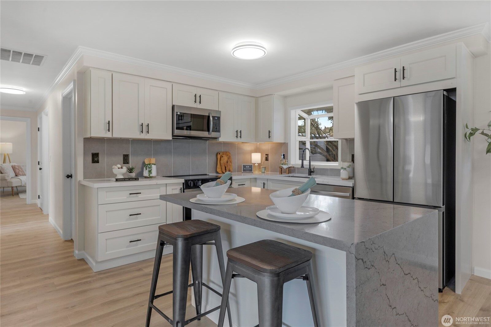 Renovated kitchen with quartz waterfall island and stainless appliances